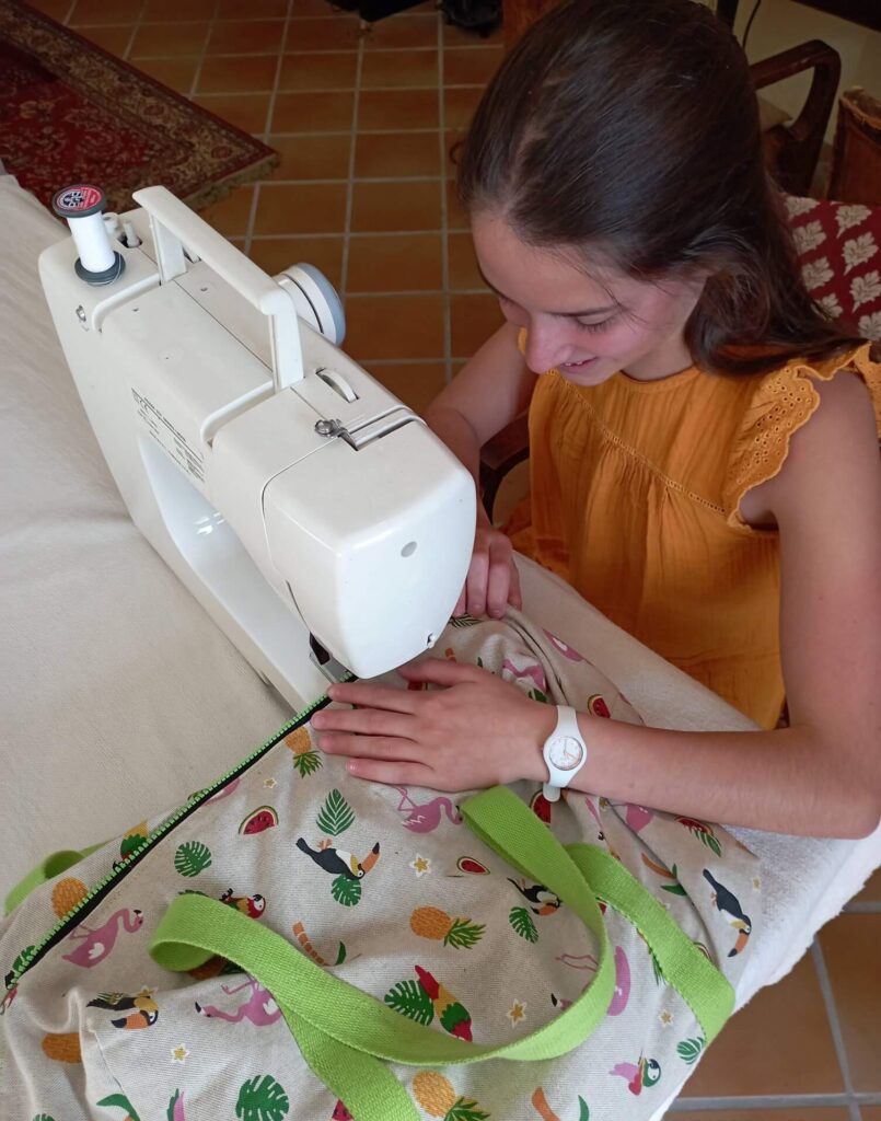 Une élève lors d'un cours particulier de couture en Haute-Savoie. Elle est en train de coudre un sac de sport dans un tissu imprimé tropical